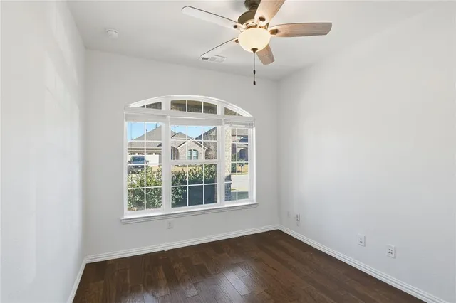 an empty room with wooden floor fan and a window
