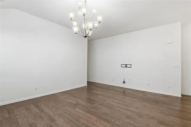 an empty room with wooden floor and chandelier