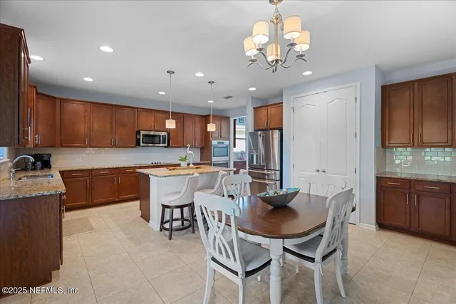 a kitchen with stainless steel appliances granite countertop a sink dishwasher a stove a refrigerator oven a dining table and chairs with wooden floor