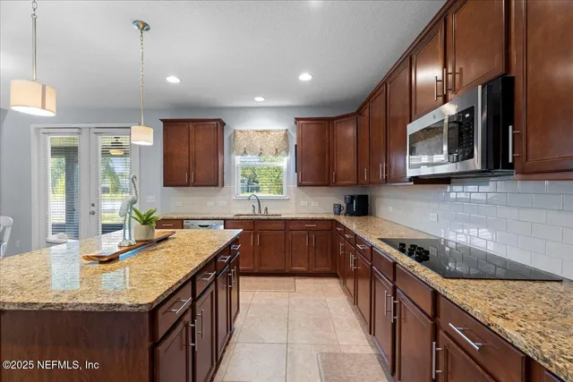 a kitchen with granite countertop kitchen island a sink a counter space appliances and cabinets