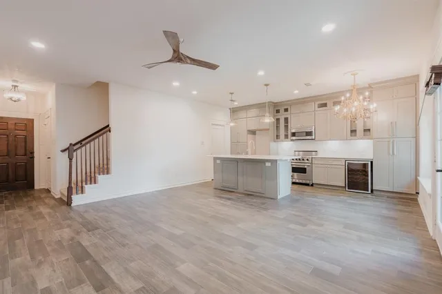 a view of a kitchen with stainless steel appliances wooden floor and a refrigerator