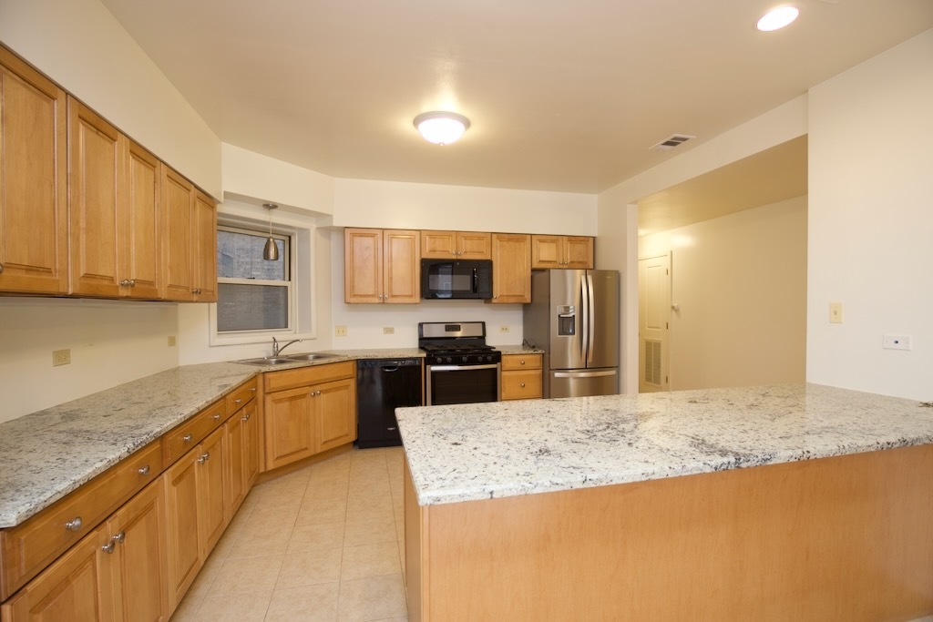 6711 North Sheridan Road, Unit 3S Chicago, IL 60626 - Photo 2 of 20 a large kitchen with granite countertop a sink and dishwasher a stove top oven with wooden floor