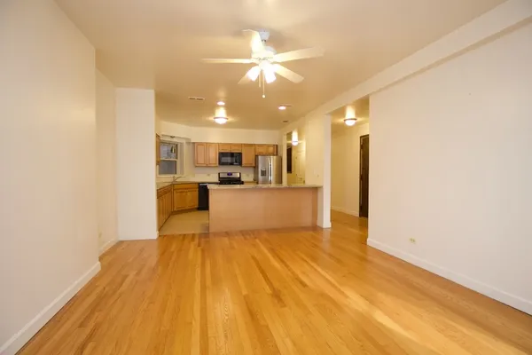 a view of a kitchen with kitchen island a sink wooden floor and stainless steel appliances