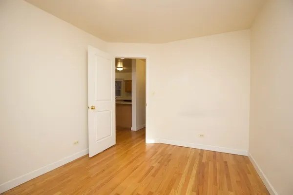 a view of an empty room with wooden floor and closet