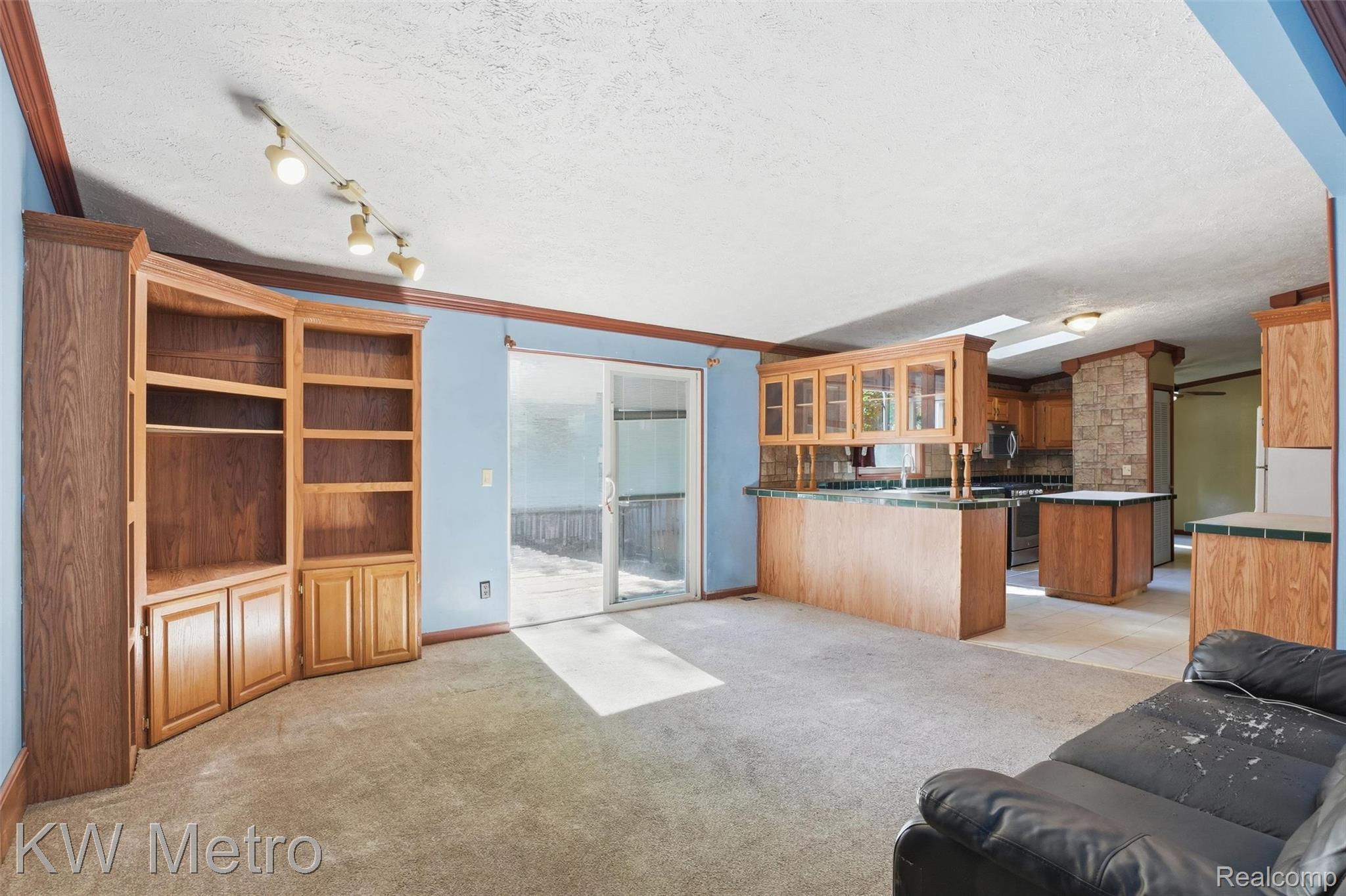 22733 Sumpter Road Belleville, MI 48111 - Photo 26 of 52 Built-in wood cabinetry with shelving, track lighting, sliding glass door, kitchen area with wood-finish cabinetry, and stone-finish pillar