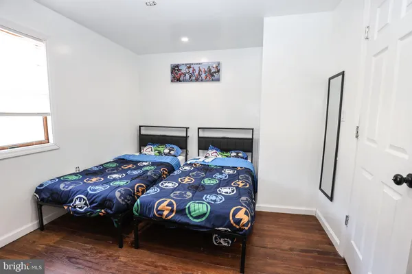 a bedroom with a bed a dresser with wooden floor