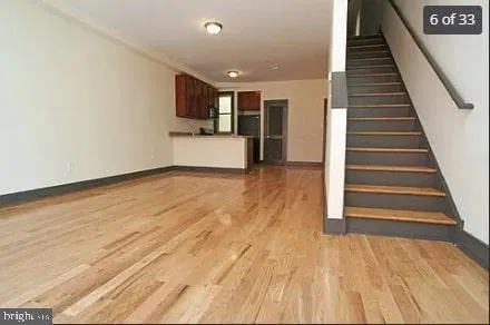 a view of a livingroom with wooden floor and stairs