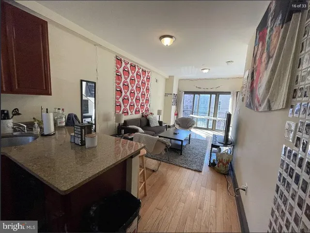 a view of kitchen island with stainless steel appliances granite countertop sink stove refrigerator and wooden floor
