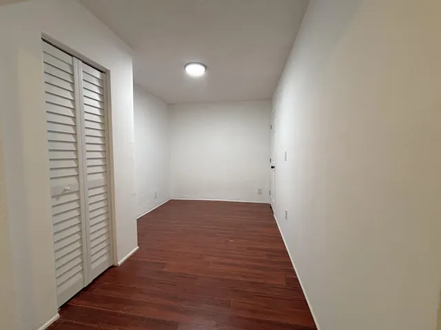a view of a hallway with wooden floor and a window
