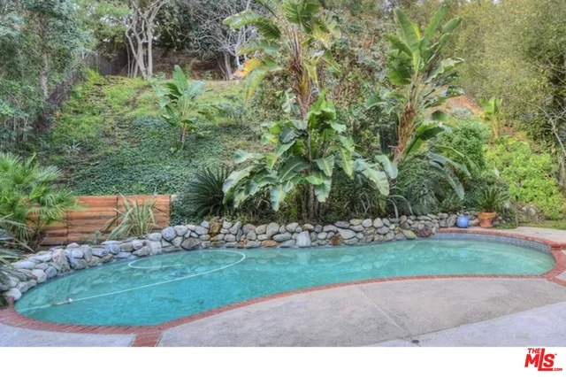 a view of a swimming pool with lawn chairs under an umbrella