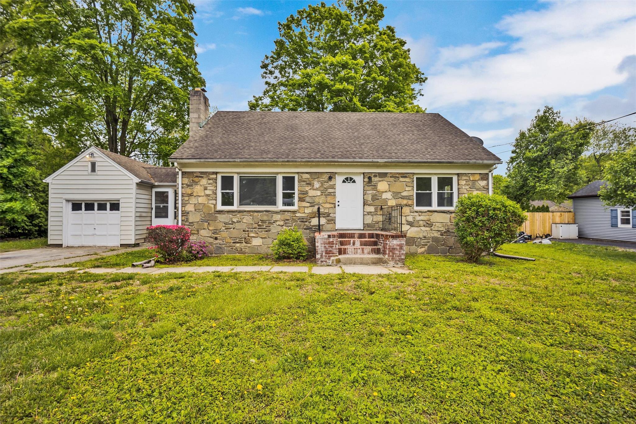 513 Vassar Road Poughkeepsie, NY 12603 - Photo 1 of 1 Cape Cod house featuring stone siding, a chimney, a shingled roof, a garage, and asphalt driveway