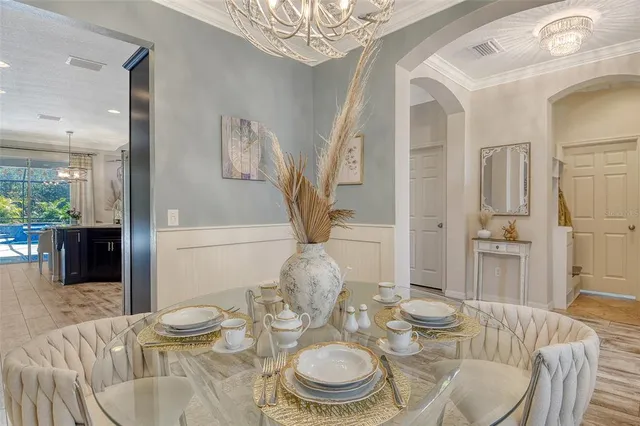 a dining room with furniture a chandelier and kitchen view