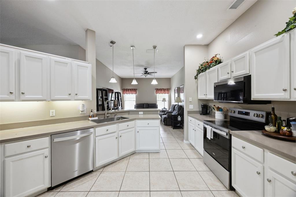 261 Mill Slough Road Oviedo, FL 32766 - Photo 14 of 62 a kitchen with stainless steel appliances granite countertop a sink and dishwasher a stove top oven with white cabinets