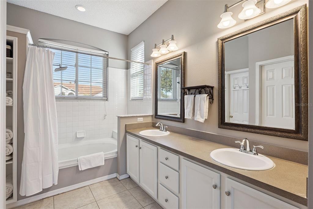 261 Mill Slough Road Oviedo, FL 32766 - Photo 26 of 62 a bathroom with double vanity sinks a large mirror and a bathtub