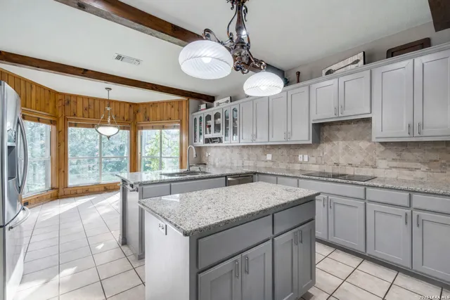 a kitchen with stainless steel appliances granite countertop a sink a stove and a wooden cabinets