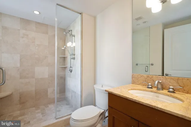 a bathroom with a granite countertop sink a toilet and shower