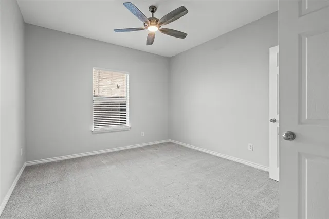 an empty room with a window and a fan