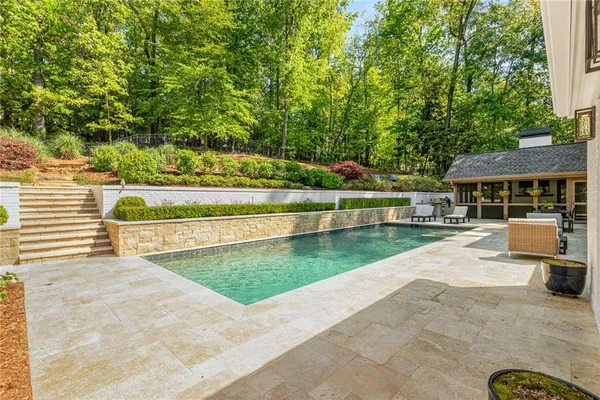 a view of swimming pool with seating area and trees in the background