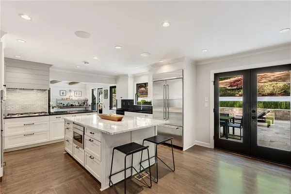 a kitchen that has a lot of white cabinets and stainless steel appliances