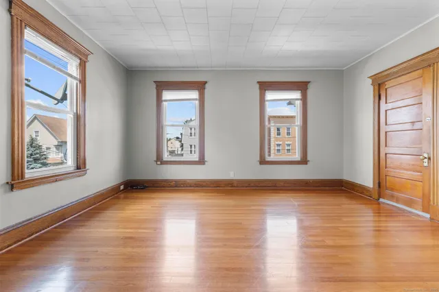 a view of an empty room with window and wooden floor