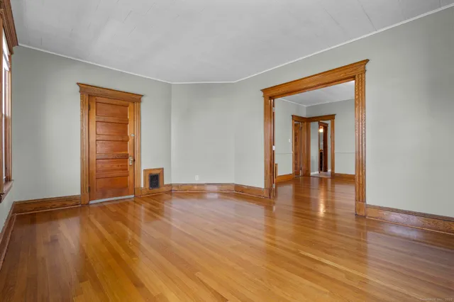 a view of an empty room with wooden floor and a window