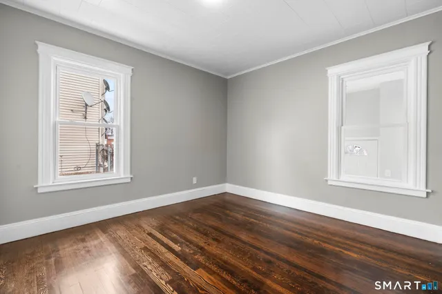 a view of empty room with wooden floor and window