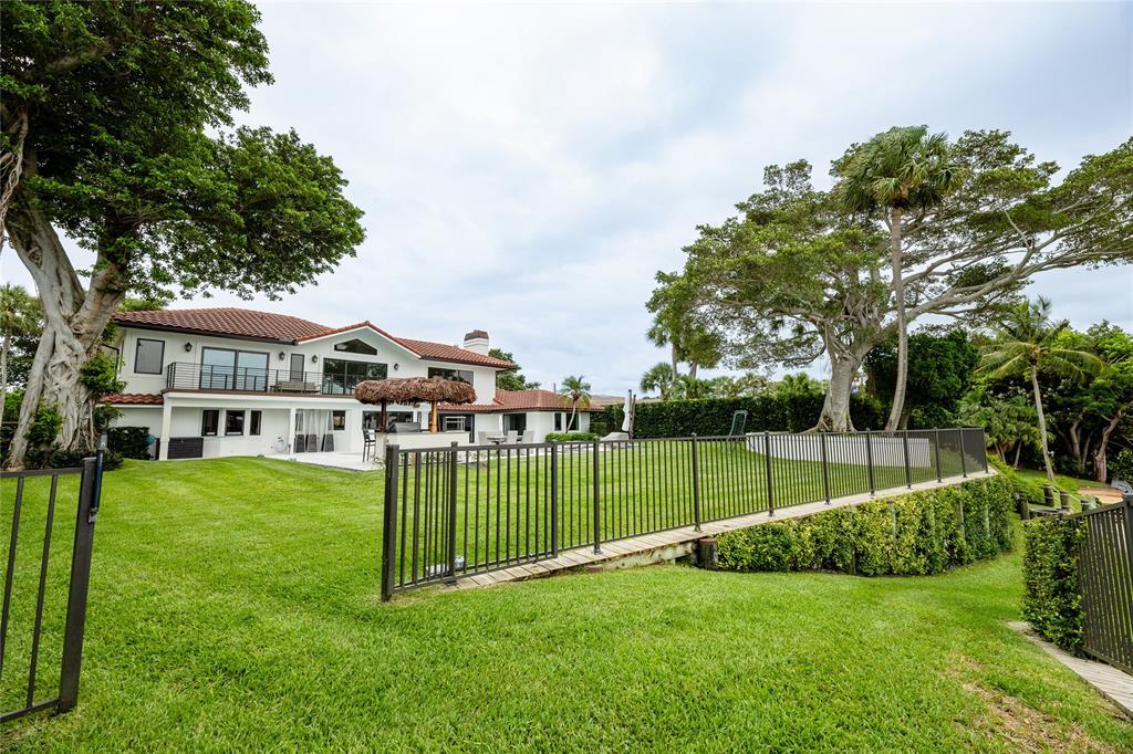 9 North River Road Stuart, FL 34996 - Photo 6 of 75 a view of a white house in a big yard with large trees and plants