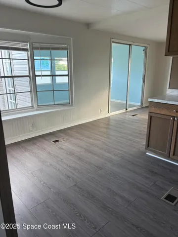 an empty room with wooden floor and windows