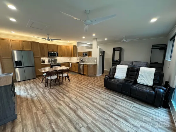 a living room with stainless steel appliances furniture and a wooden floor