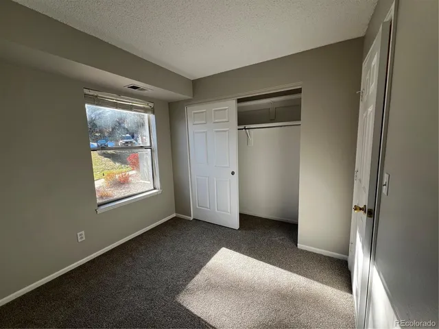 a view of an empty room with window and closet area