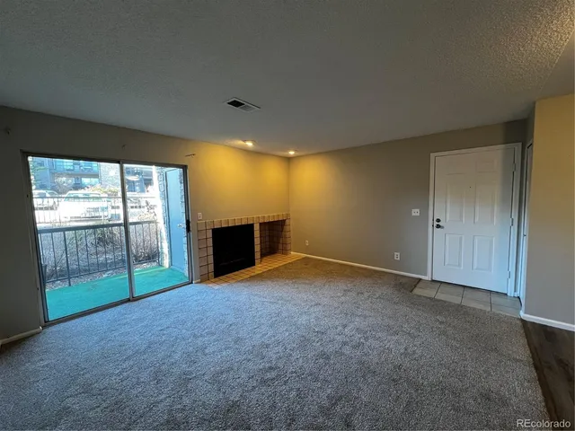 a view of an empty room with a fireplace and a window