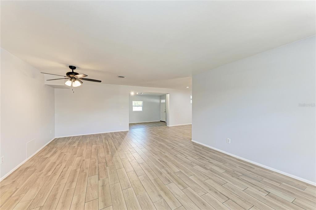 4010 South Lockwood Ridge Road Sarasota, FL 34231 - Photo 12 of 48 an empty room with wooden floor ceiling fan and windows