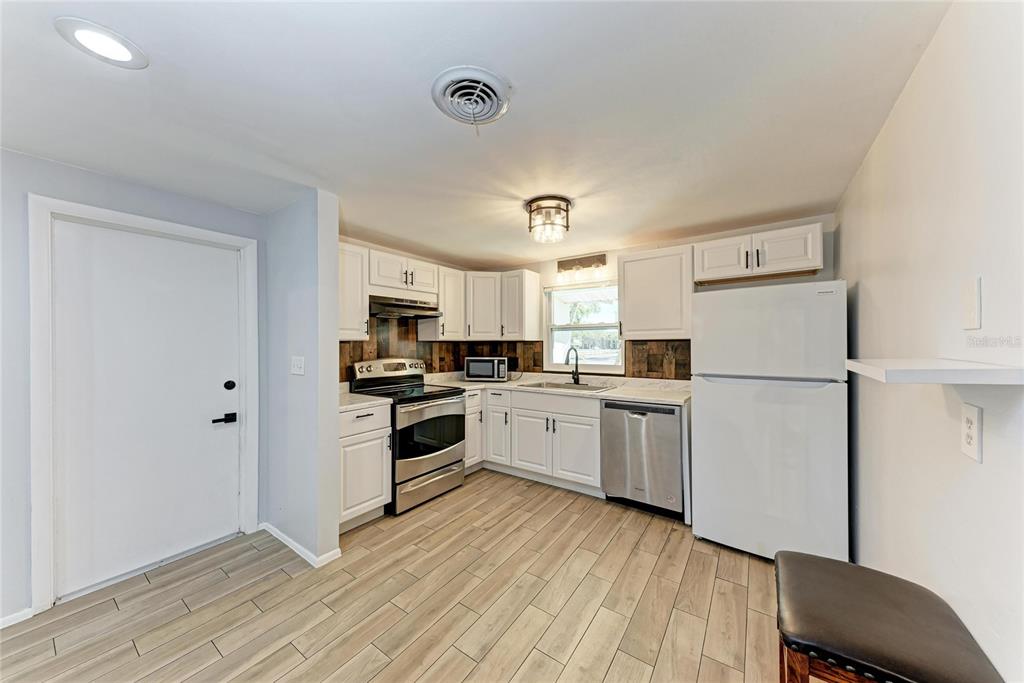 4010 South Lockwood Ridge Road Sarasota, FL 34231 - Photo 9 of 48 a kitchen with a refrigerator cabinets and wooden floor