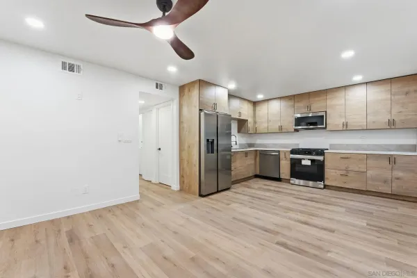 an empty room with wooden floor and a ceiling fan