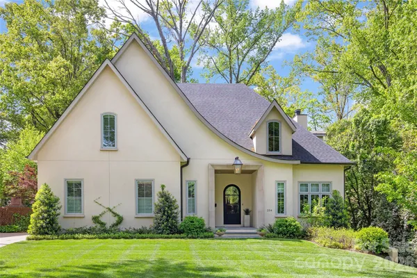 a view of a white house with a yard and potted plants