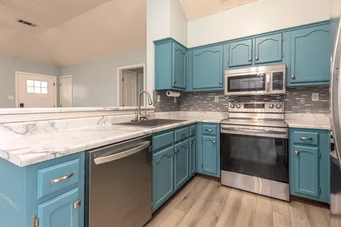a kitchen with granite countertop a sink cabinets and stainless steel appliances