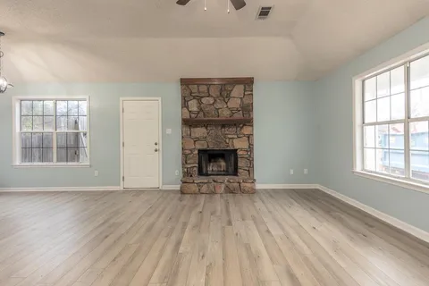 wooden floor fireplace and windows in an empty room