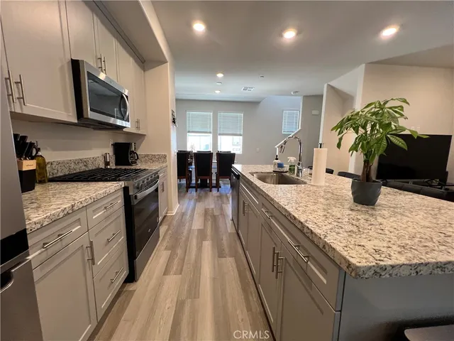 a kitchen with stainless steel appliances granite countertop a sink a stove top oven a counter space and cabinets