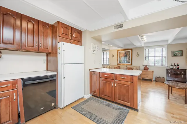 a kitchen with stainless steel appliances granite countertop a refrigerator a sink dishwasher a dining table and chairs with wooden floor