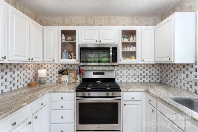a kitchen with granite countertop white cabinets stainless steel appliances and a sink