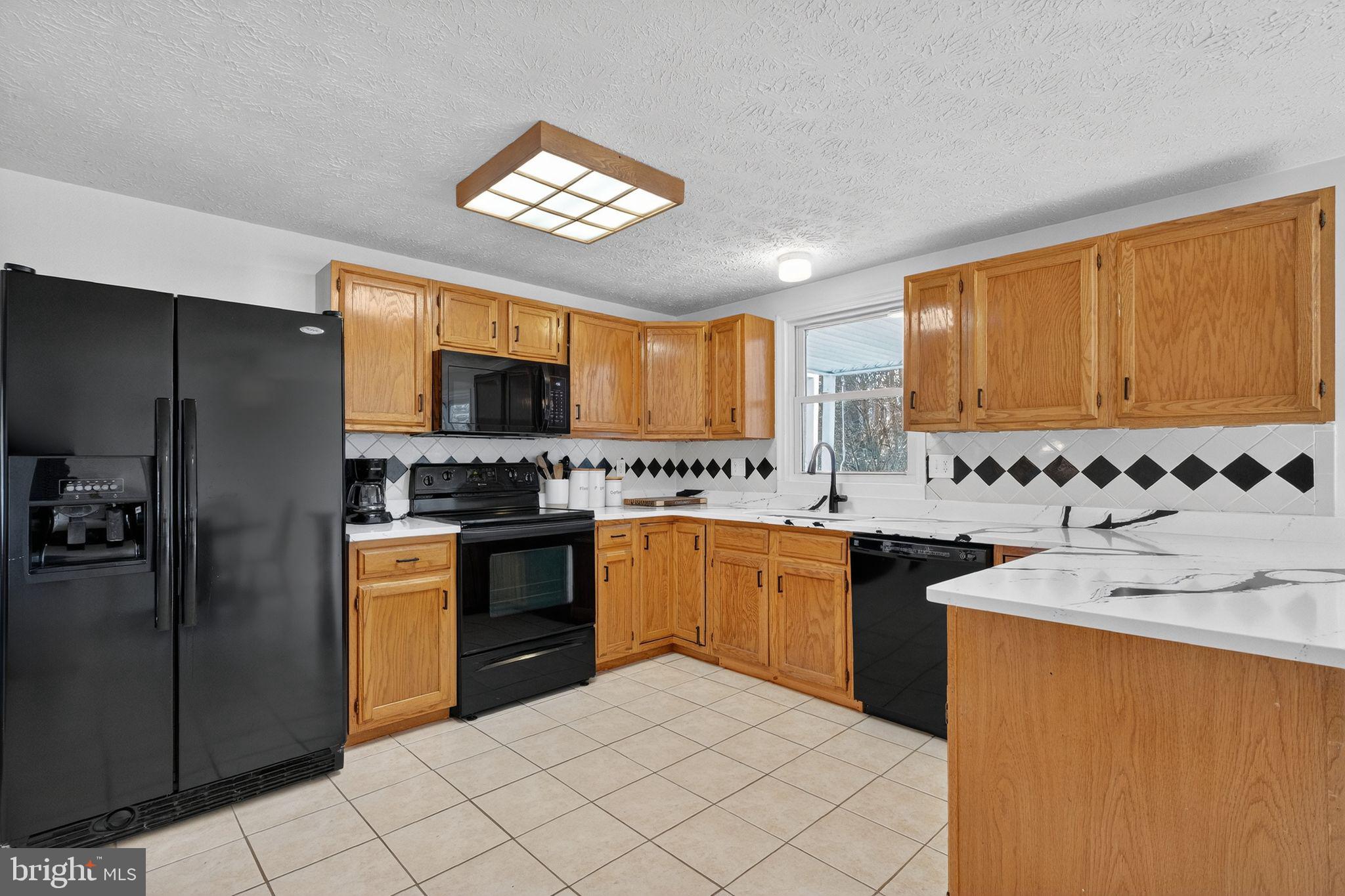12608 Carland Place Laurel, MD 20708 - Photo 5 of 38 a kitchen with stainless steel appliances granite countertop a sink a stove a refrigerator cabinets and living room view
