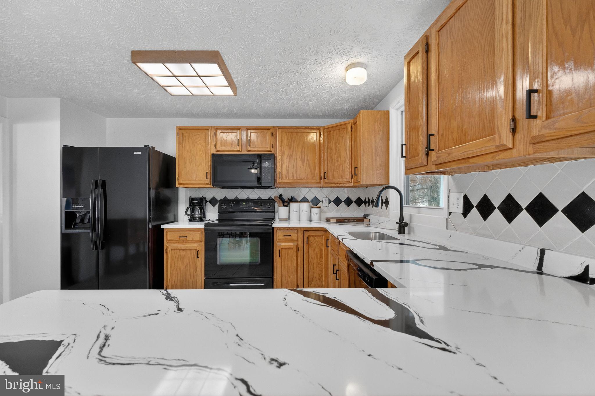 12608 Carland Place Laurel, MD 20708 - Photo 6 of 38 a kitchen with granite countertop a refrigerator and a stove top oven