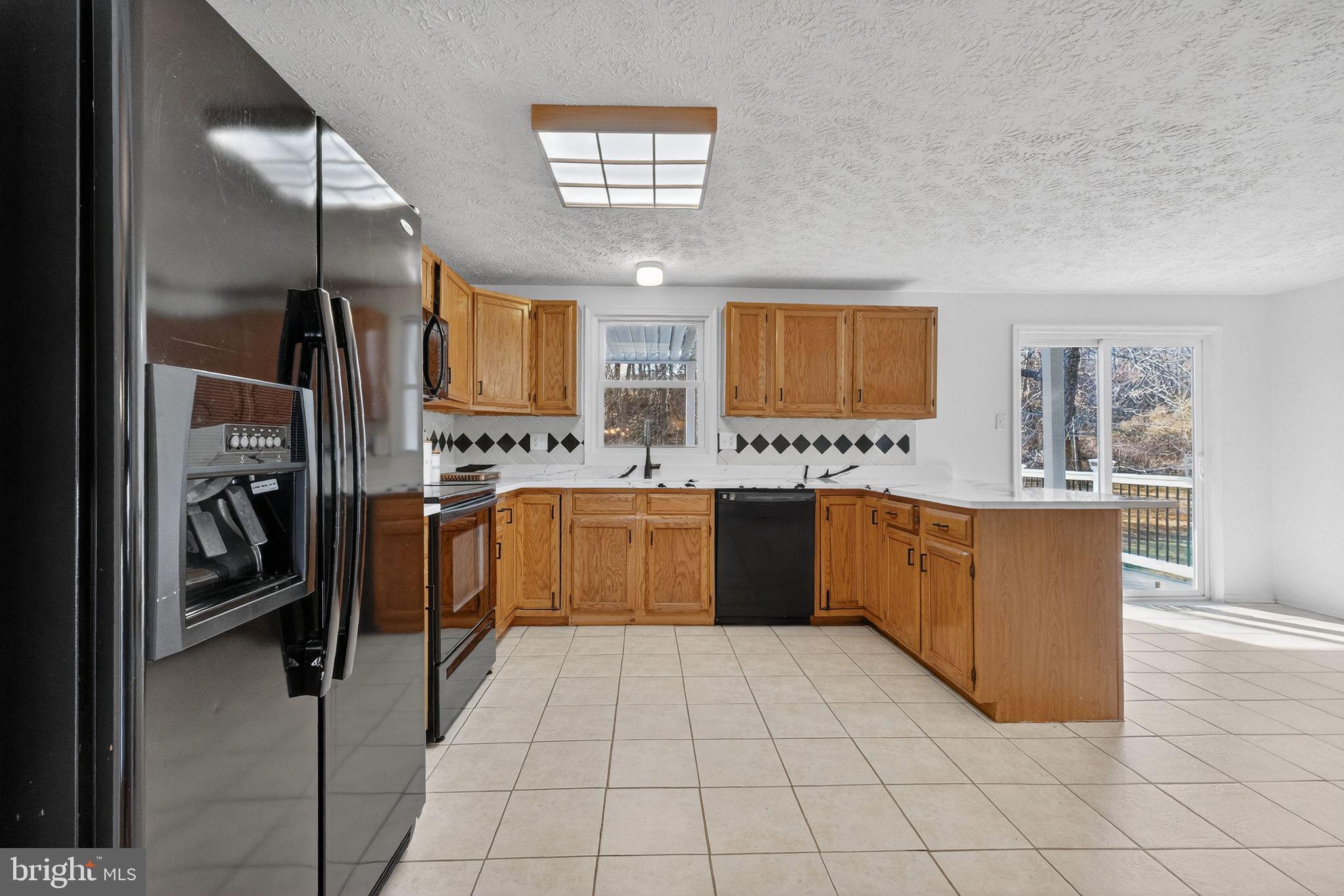 12608 Carland Place Laurel, MD 20708 - Photo 7 of 38 a large kitchen with stainless steel appliances kitchen island granite countertop a refrigerator and a sink