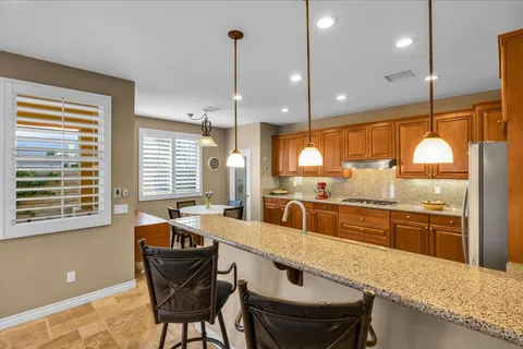 a kitchen with stainless steel appliances granite countertop a sink a stove and a wooden cabinets