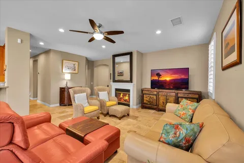 a living room with furniture a ceiling fan and a flat screen tv