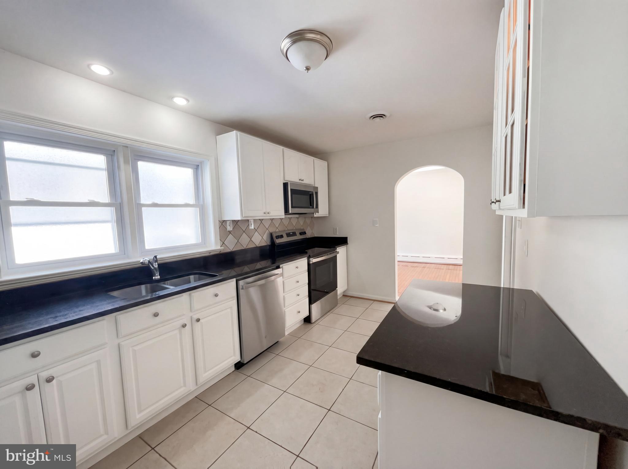 6048 Old Telegraph Road Alexandria, VA 22310 - Photo 3 of 43 a large kitchen with stainless steel appliances a sink dishwasher and white cabinets with wooden floor