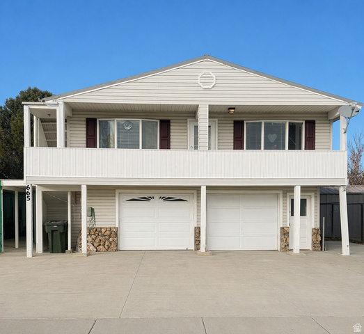 View of front of home with stone siding, a garage, and concrete driveway