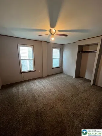 an empty room with windows and fan
