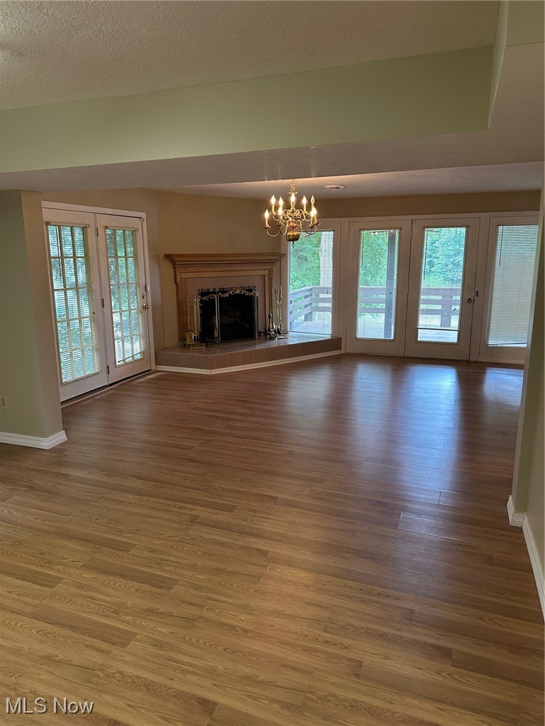 1224 Ridge Road Salem, OH 44460 - Photo 37 of 48 Unfurnished living room featuring wood finished floors, a chandelier, french doors, a fireplace with raised hearth, and a textured ceiling