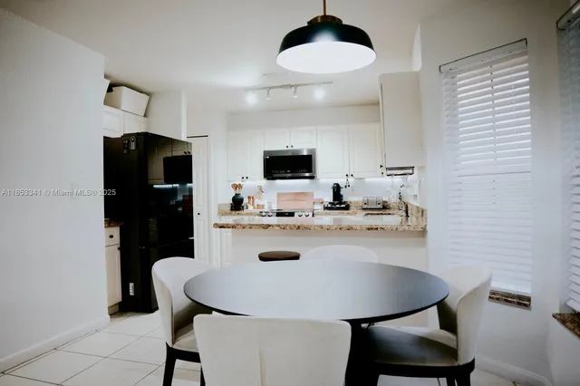 a kitchen with stainless steel appliances a dining table chairs and granite counter tops